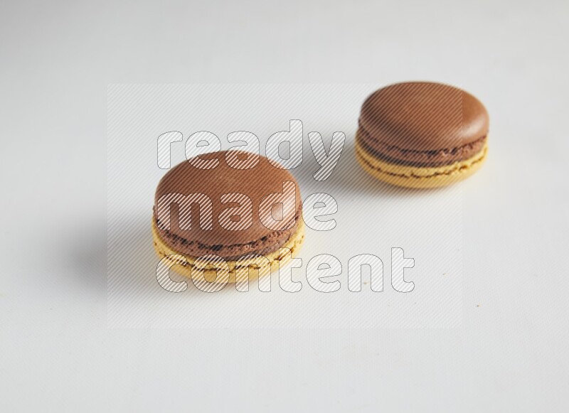 45º Shot of two Yellow and Brown Chai Latte macarons on white background