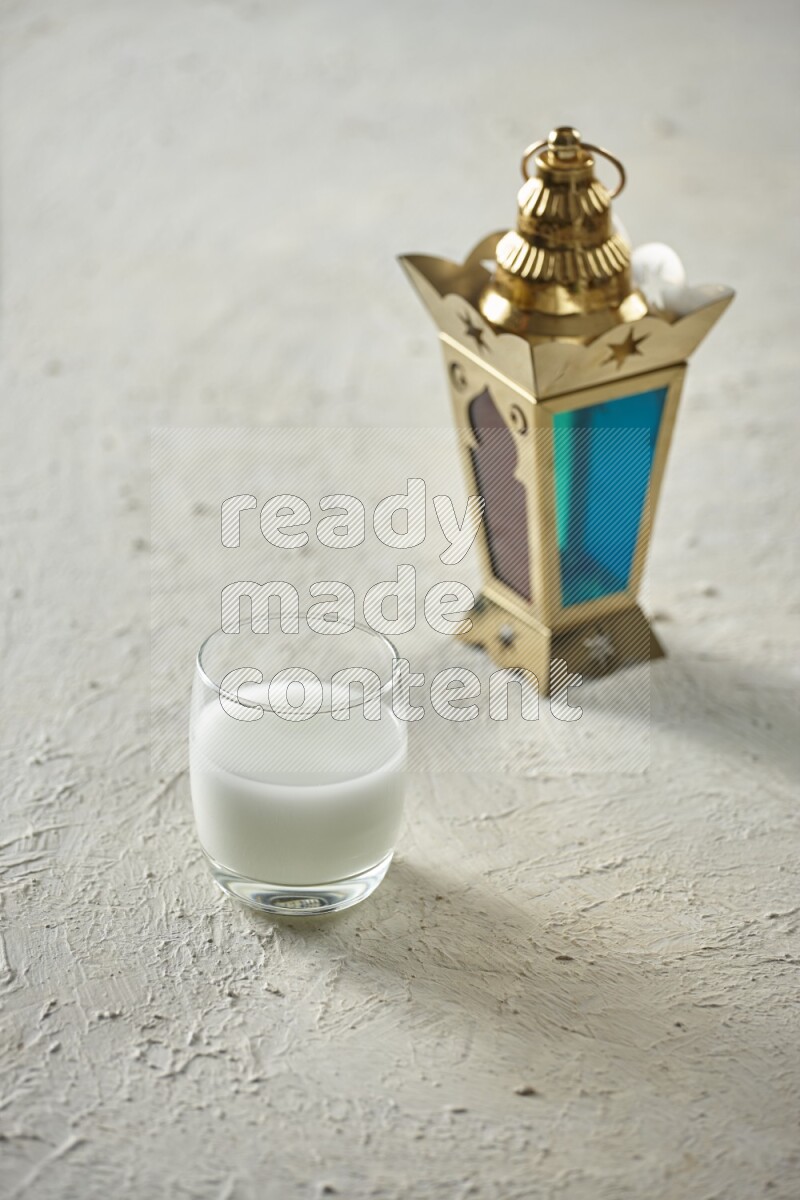 A golden lantern with different drinks, dates, nuts, prayer beads and quran on textured white background