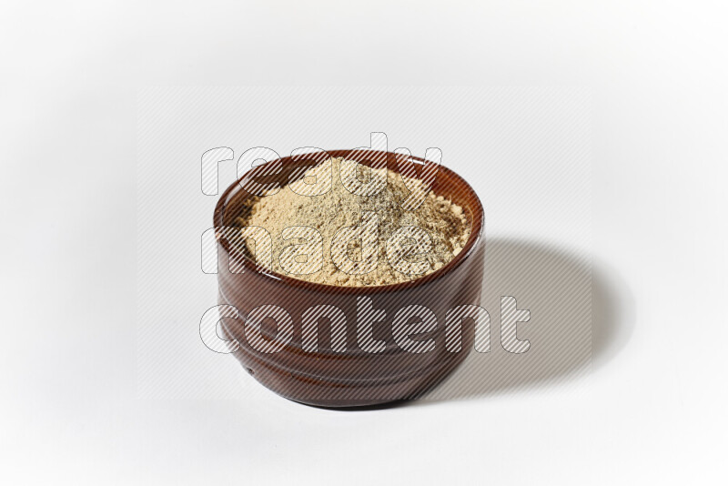 A brown pottery bowl full of ground ginger powder on white background