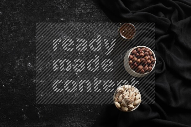 مكسرات في أطباق فخارية مع القهوة علي خلفية سوداء خشبية