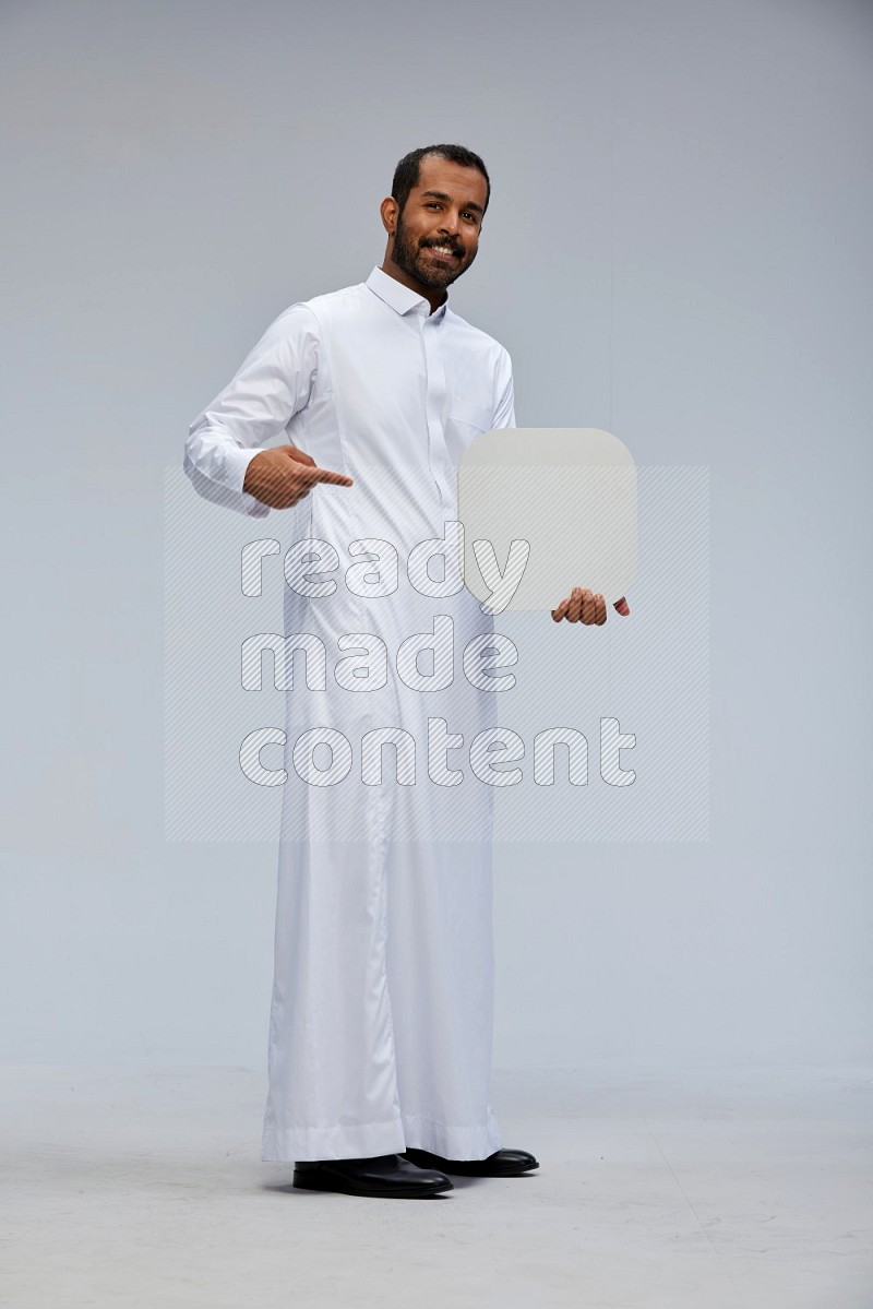 Saudi man wearing Thob standing holding social media sign on Gray background