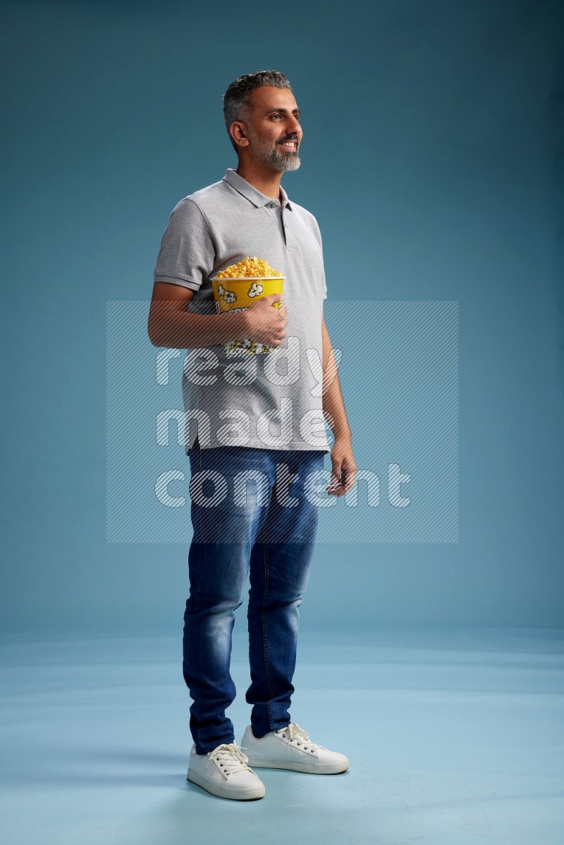 Man Standing eating popcorn on blue background