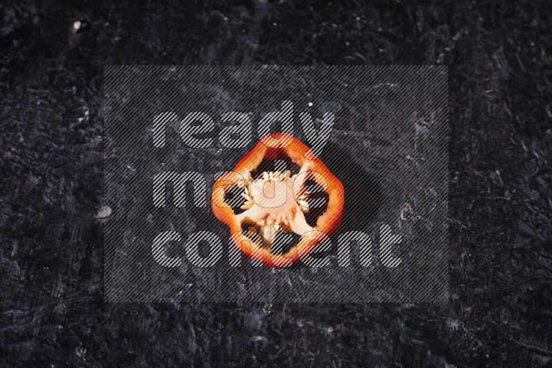 Red bell pepper slices on black background