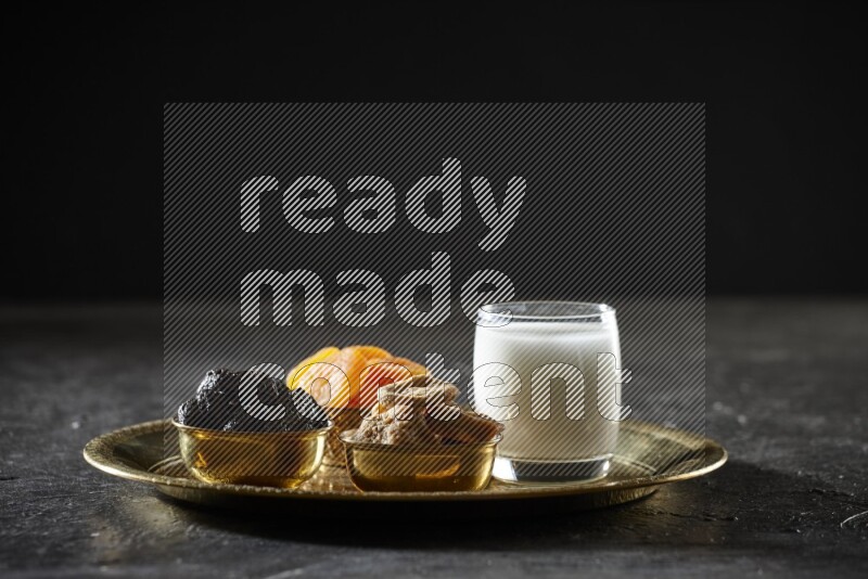 Dried fruits in metal bowls with sobya on a tray in dark setup