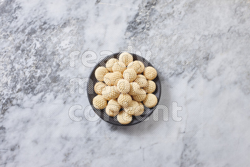 كحك في صحن فخار أسود على خلفية رخام رمادي