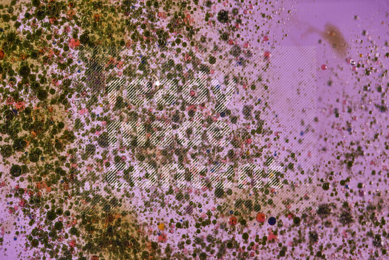 لقطات مقربة لقطرات ألوان مائية خضراء وحمراء على سطح الزيت على خلفية وردية