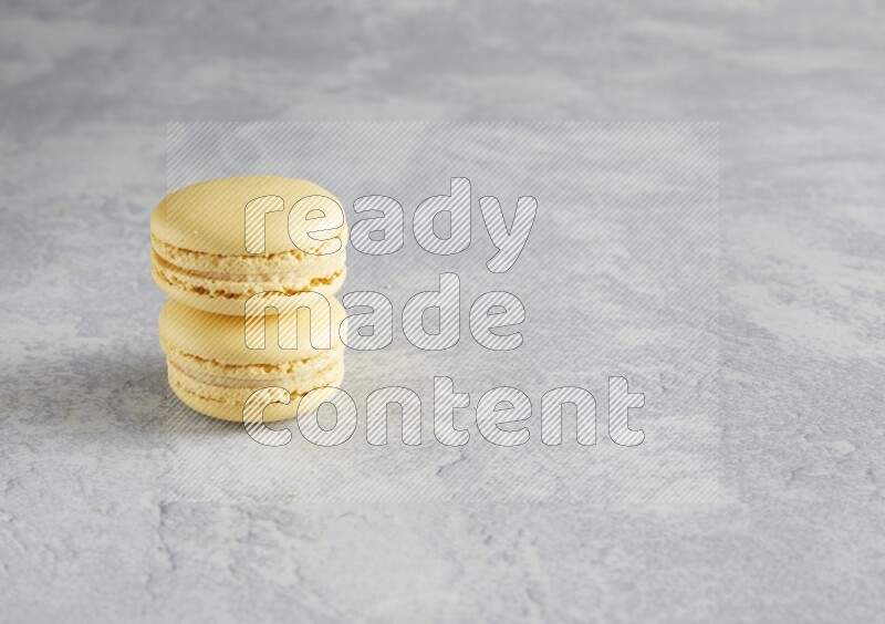 45º Shot of two Yellow Vanilla macarons  on white  marble background