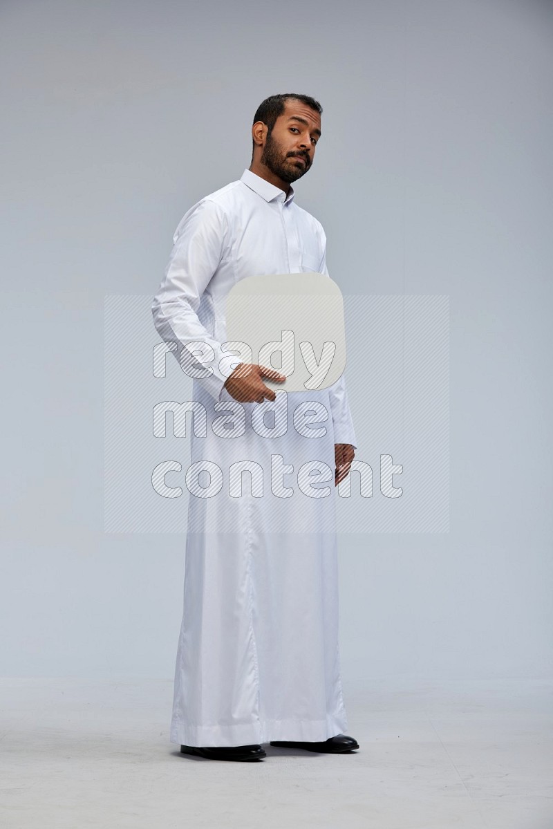 Saudi man wearing Thob standing holding social media sign on Gray background