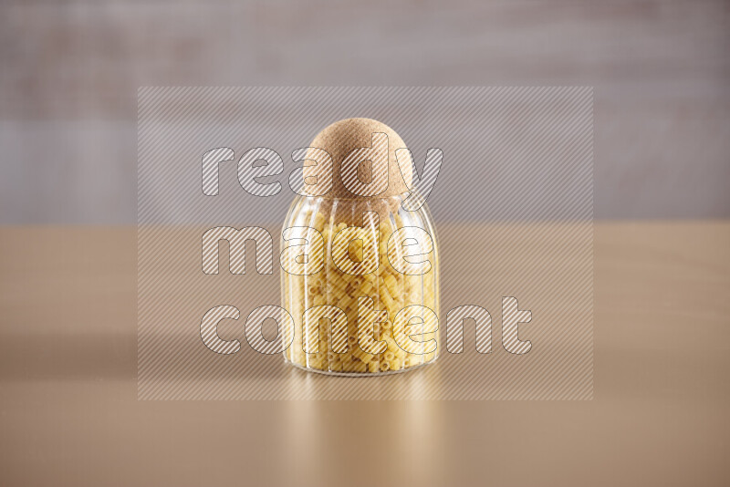 Raw pasta in glass jars on beige background