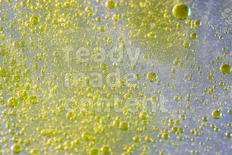 Close-ups of abstract yellow watercolor drops on oil Surface on white background