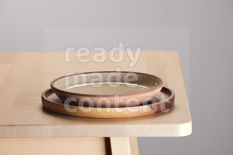 multi-colored pottery Plate placed on a light colored wooden tray on the edge of wooden table