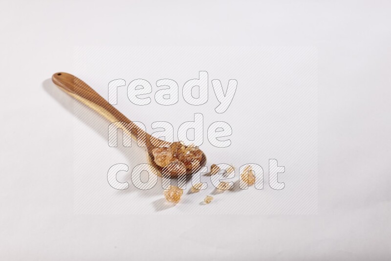 A wooden ladle filled with gum arabic on white flooring