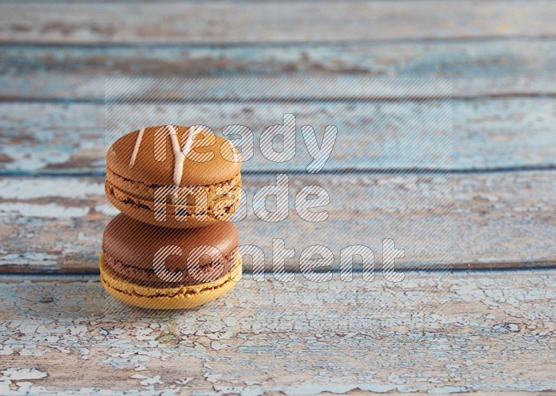 45º Shot of of two assorted Brown Irish Cream, and Yellow, and Brown Chai Latte macarons  on light blue background