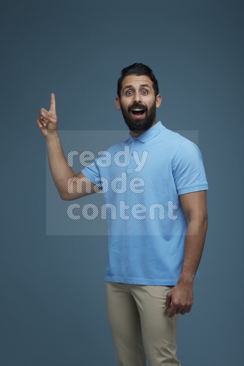 A man pointing  in a blue background wearing a Blue shirt