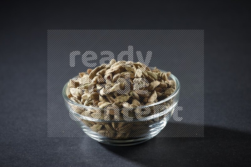 A glass bowl full of cardamom on black flooring