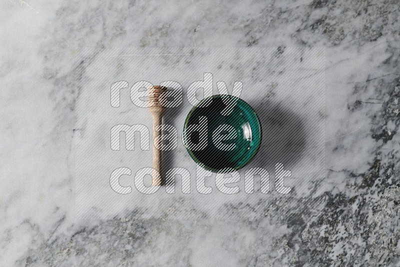 Dark green Pottery Bowl with wooden honey handle on the side on grey marble flooring, Top view