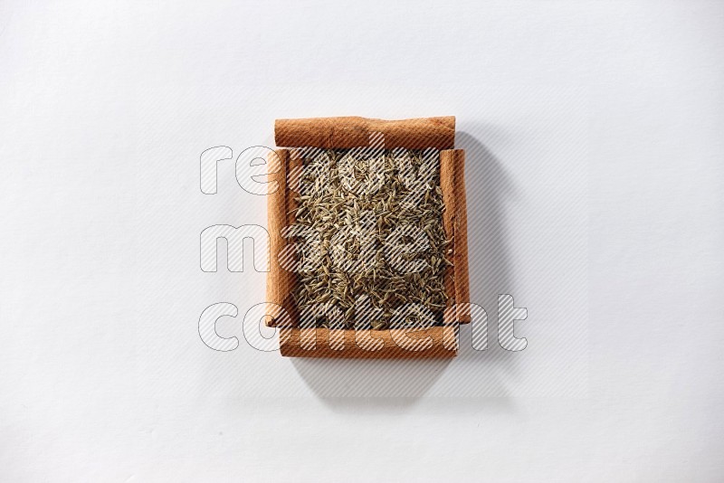 A single square of cinnamon sticks full of cumin on white flooring