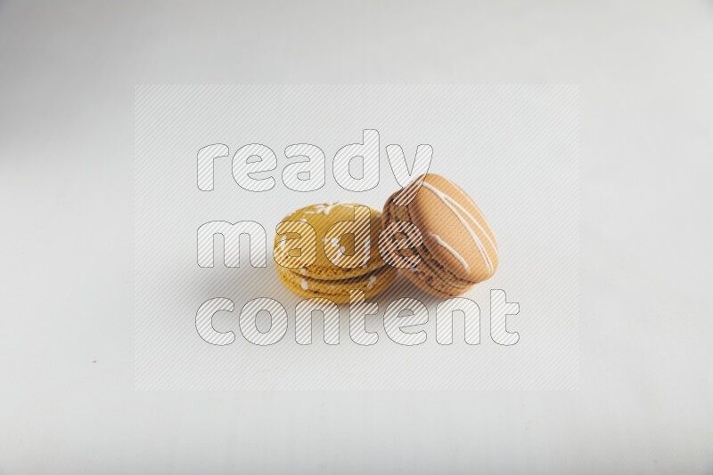 45º Shot of of two assorted Brown Irish Cream, and Yellow Piña Colada macarons on white background