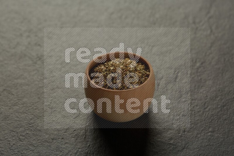 wooden round sauce bowl filled with herbs on grey textured countertop
