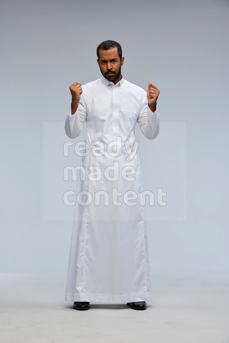 Saudi man Wearing Thob standing interacting with the camera on Gray background