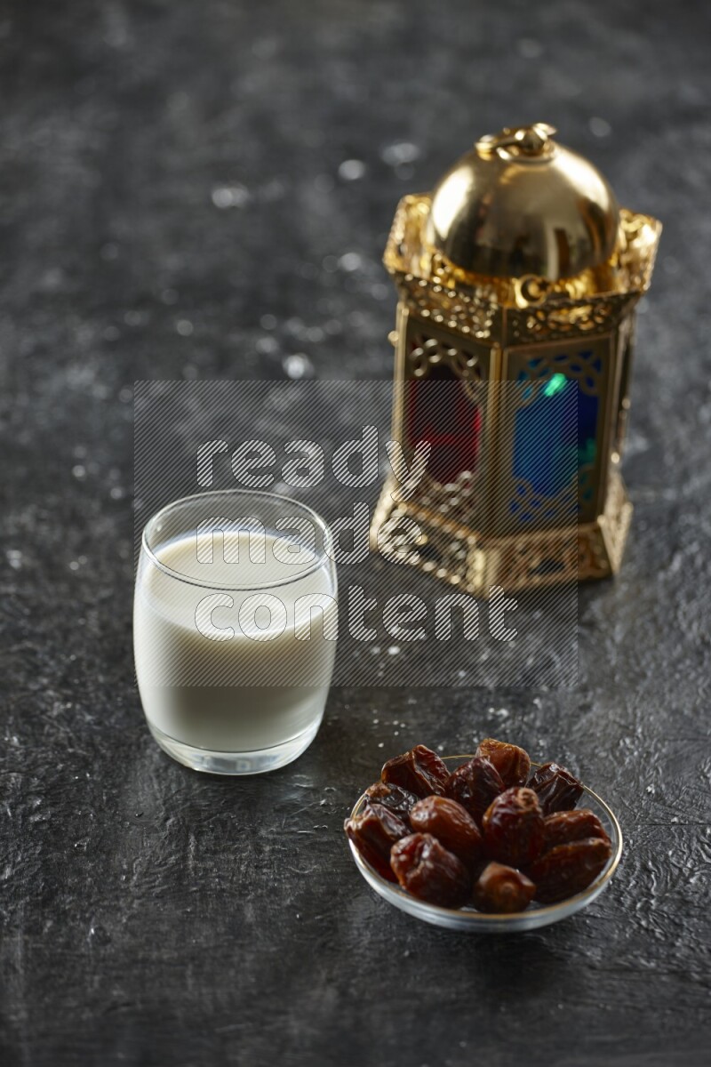 A golden lantern with different drinks, dates, nuts, prayer beads and quran on textured black background