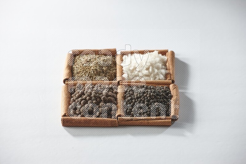 4 squares of cinnamon sticks full of cumin, white salt, allspice and black pepper on white flooring