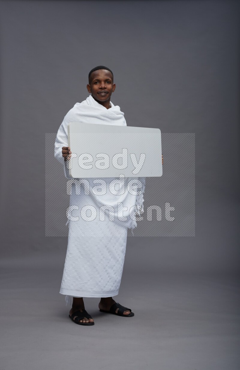 A man wearing Ehram Standing holding board sign on gray background