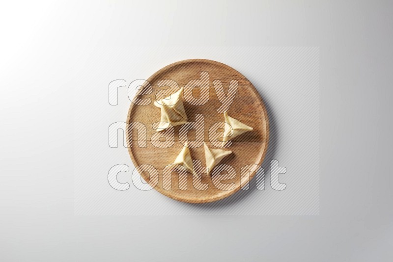 Five Sambosas on a wooden round plate on a white background