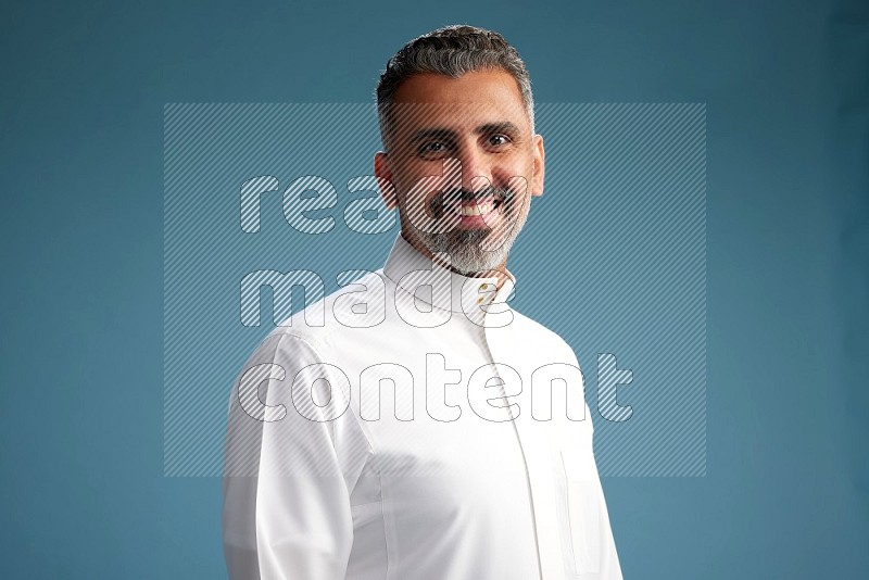 Saudi man waring thob posing to the camera on blue background
