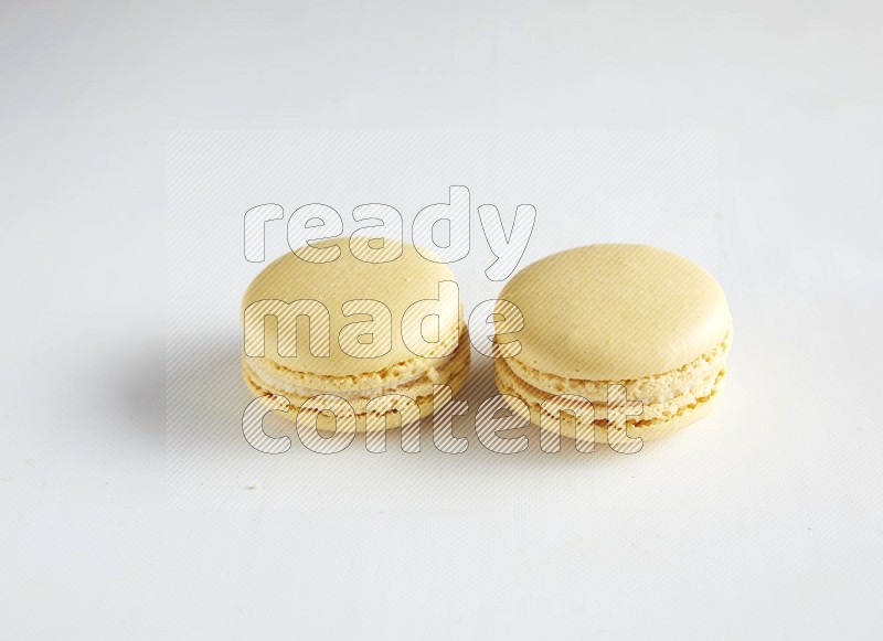 45º Shot of two Yellow Vanilla macarons on white background