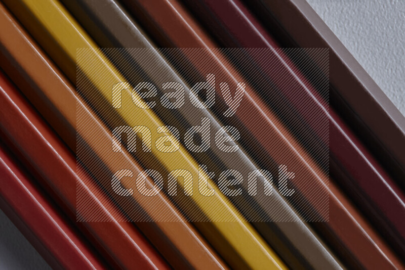 A collection of colored pencils arranged showcasing a gradient of brown hues on grey background
