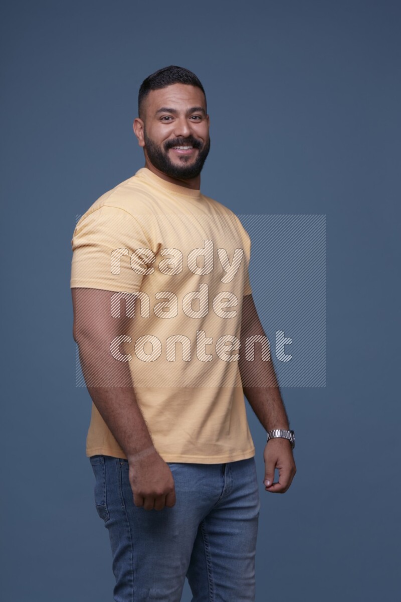 رجل يرتدي قميص اصفر بأكمام قصيرة وبنطال جينز ازرق يقف بأوضاع مختلفة