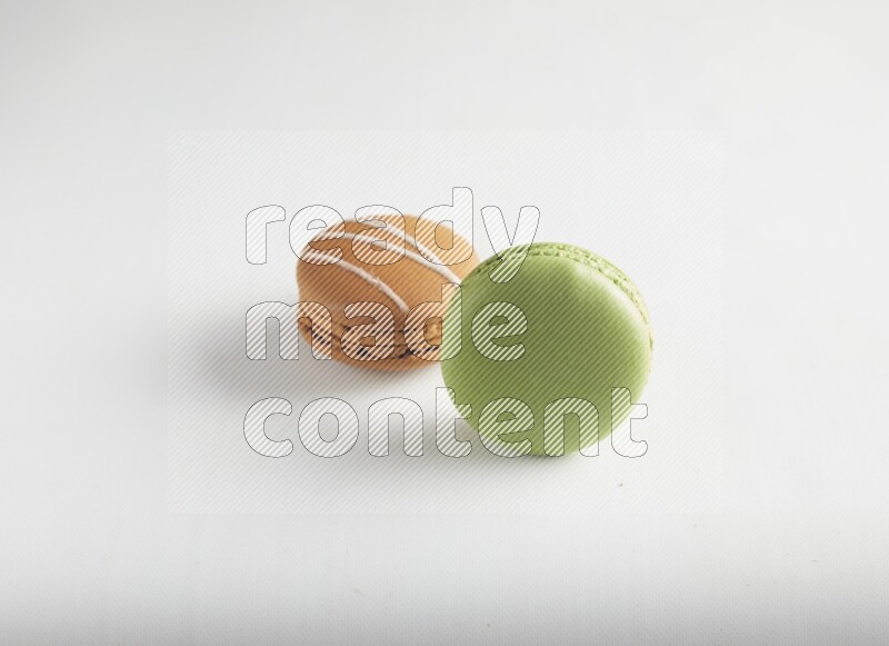 45º Shot of of two assorted Brown Irish Cream, and Green Pistachio macarons on white background
