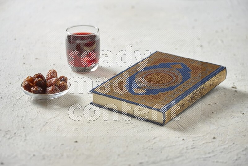 Quran with dates, prayer beads and different drinks all placed on textured white background
