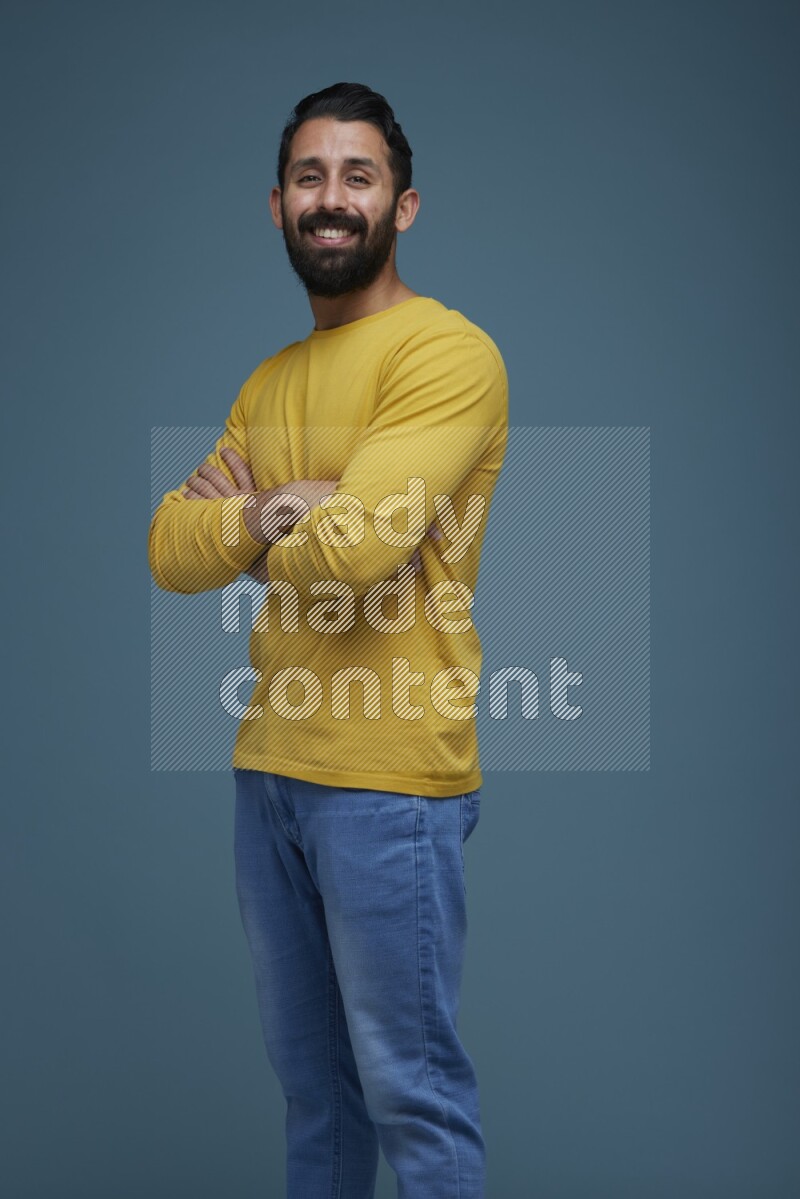 Man posing in a blue background wearing a yellow shirt