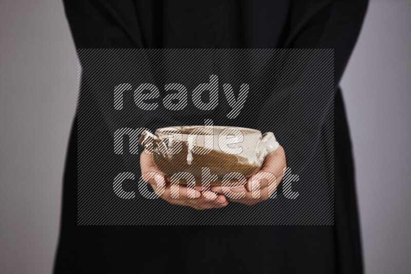 A woman in black abaya holding different pottery essentials in different positions