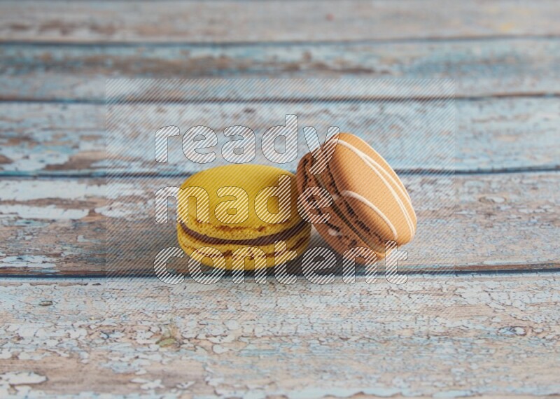 45º Shot of of two assorted Brown Irish Cream, and Yellow Lemon macarons on light blue background