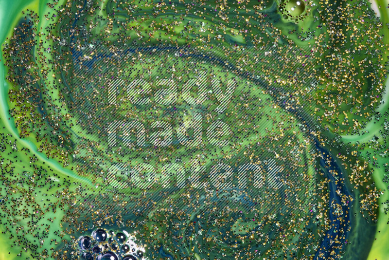 A close-up of sparkling gold glitter scattered on swirling blue and green background