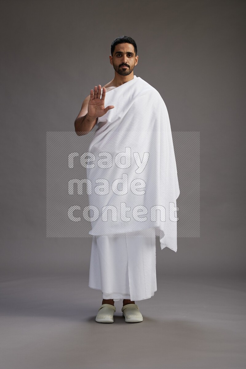 A man wearing Ehram Standing Interacting with the camera on gray background
