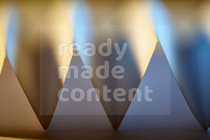 صورة مجردة مقربة تظهر طيات ورقية هندسية حادة بتدرجات اللون الأزرق مع درجات لونية دافئة