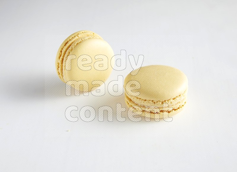 45º Shot of two Yellow Vanilla macarons on white background