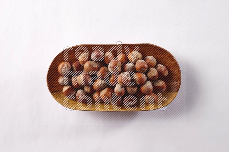 Hazelnuts in a wooden plate on white background