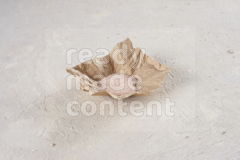 A crumpled piece of paper full of pink himalayan salt on white background