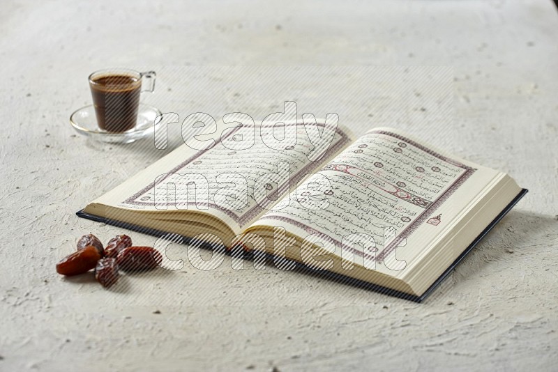 Quran with dates, prayer beads and different drinks on textured white background