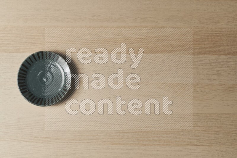 A dark green pottery plate on light wooden background