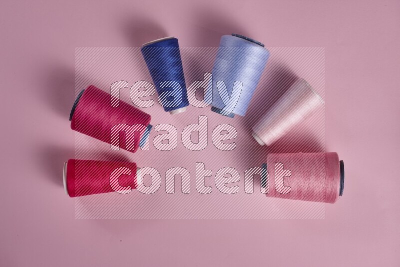 A blue collection of sewing and tailoring tools arranged on a pink background