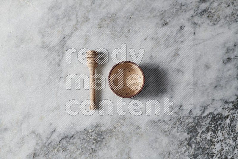 Beige Pottery Oven Bowl Plate with wooden honey handle on the side on grey marble flooring, Top view