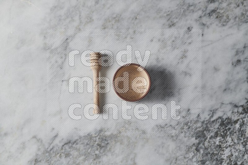 Beige pottery oven bowl with wooden honey dipper on the side on grey marble background