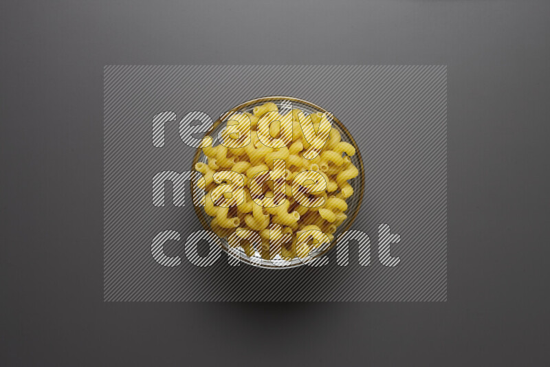 Twist pasta in a glass bowl on grey background