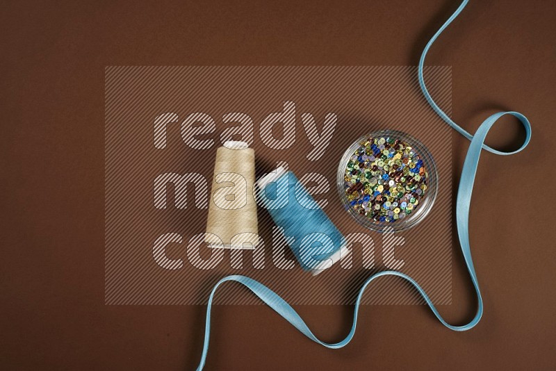 Blue sewing supplies on brown background